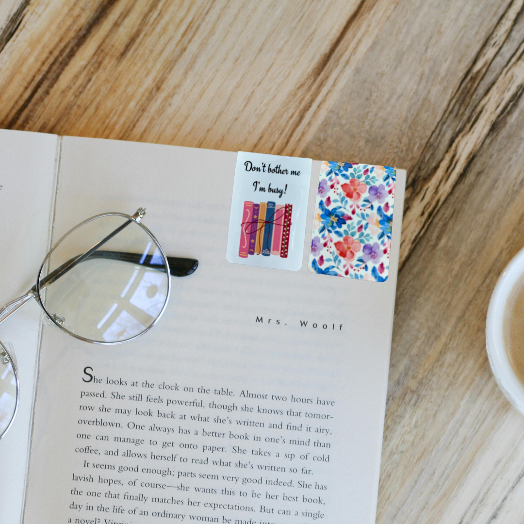 Magnetic bookmark with “Don’t bother me I’m busy” quote and floral back shown on open book with glasses