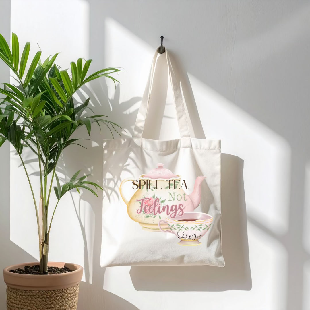 Canvas tote hanging on wall hook with words "spill tea, not feelings" on top of a tea pot.