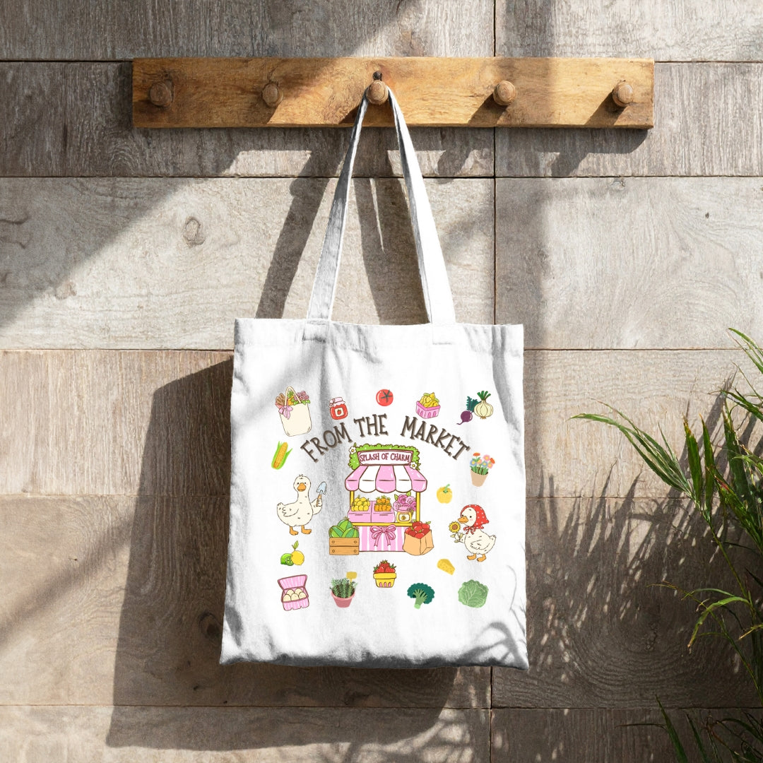 Lifestyle image of the From the Market reusable canvas tote hanging outdoors with the colorful market-inspired design displayed on the front.