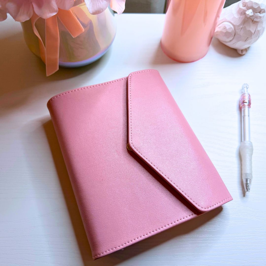 Closed Bailey Clutch™ faux leather A6 organizer with the Daily Sidekick™ System by Splash of Charm, shown with a coordinating pen.