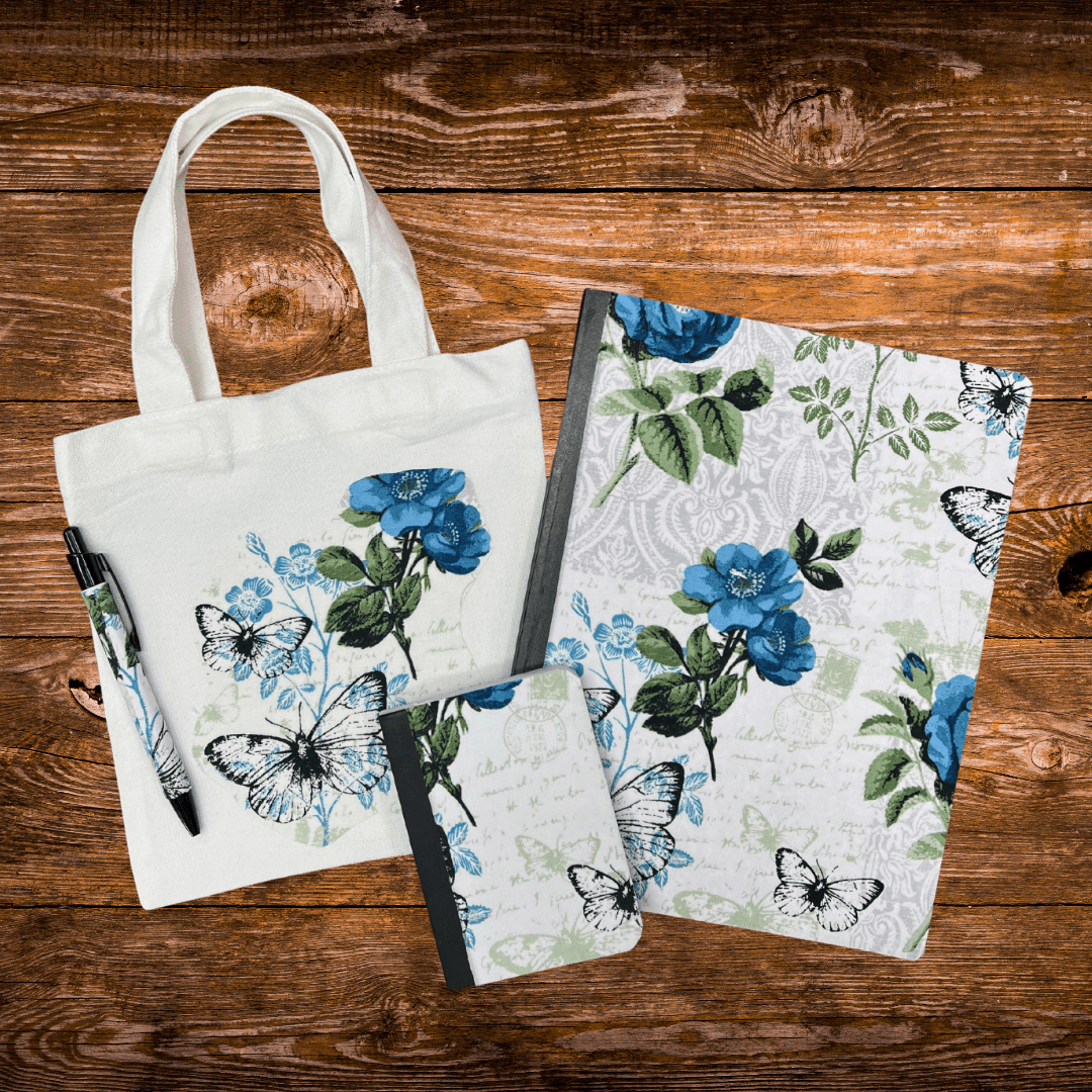 Blue floral mini tote bag holding journal and pen with butterfly design on wooden background