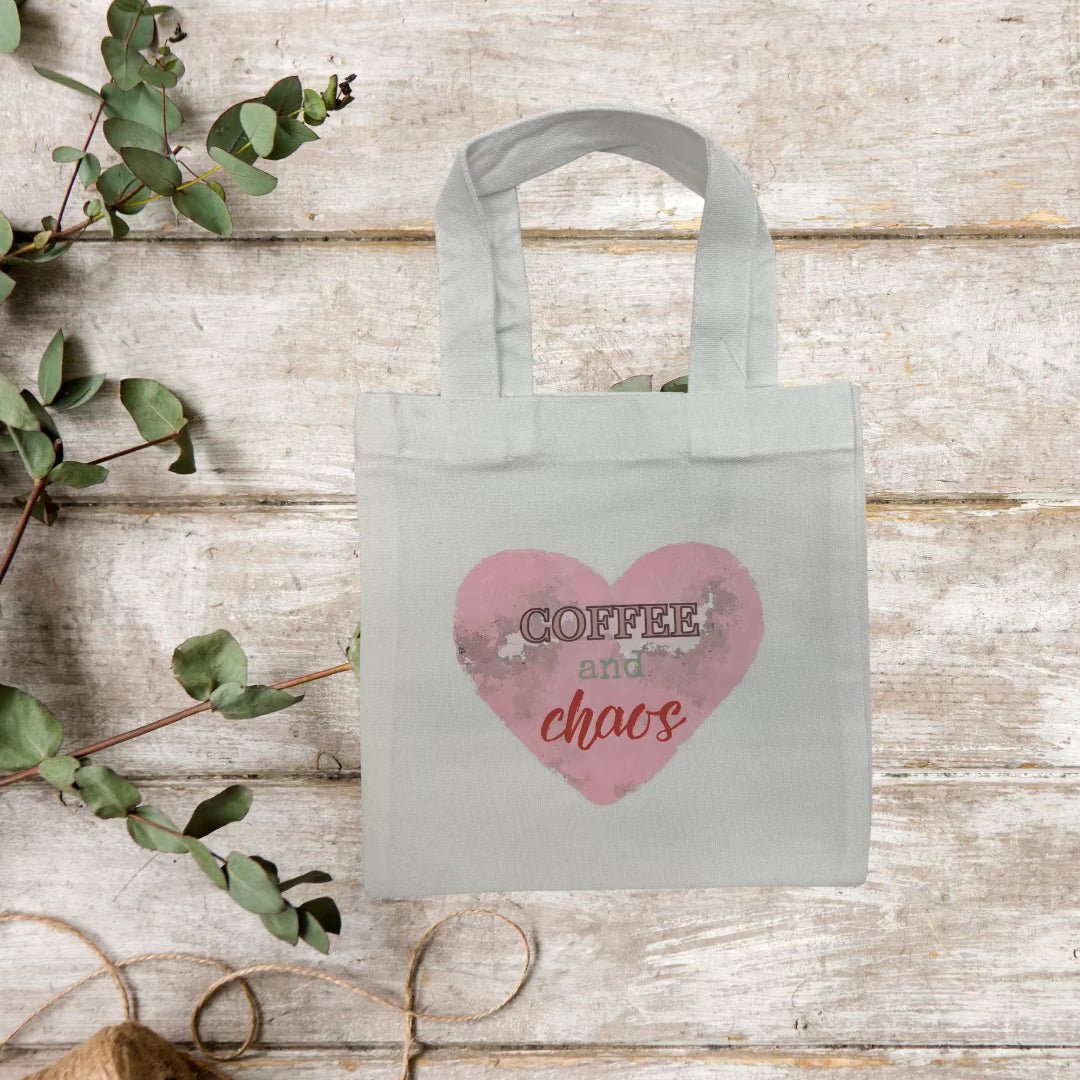 Wood background with a tote with a pink heart and words "coffee and chaos."