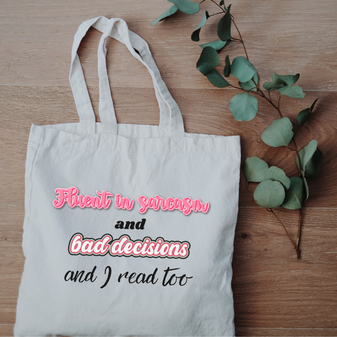 Mini canvas tote bag with “Fluent in sarcasm and bad decisions and I read too” design on wooden background