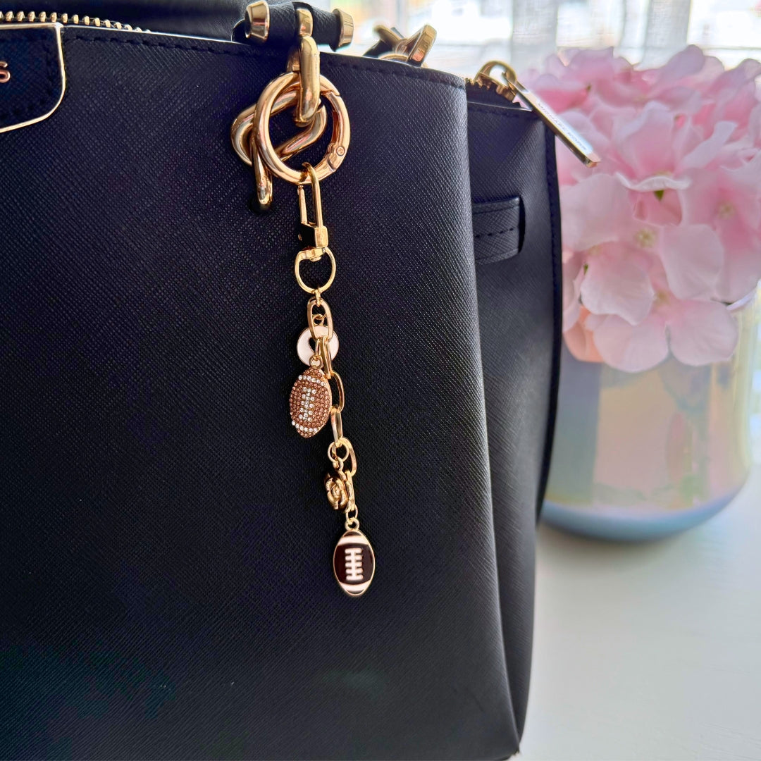 Handmade football purse charm attached to a black handbag showing how the accessory looks during everyday use.