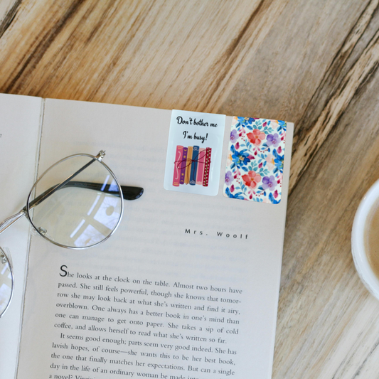 Magnetic bookmark with “Don’t bother me I’m busy” quote and floral back shown on open book with glasses