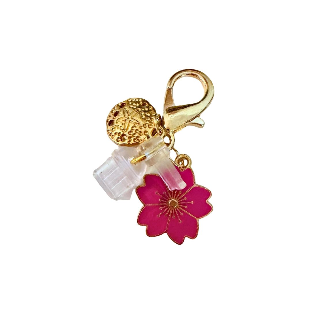 Phone dust cover charm with a pink blossom, gold-tone sand dollar, clear port covers, and gold-tone lobster clasp