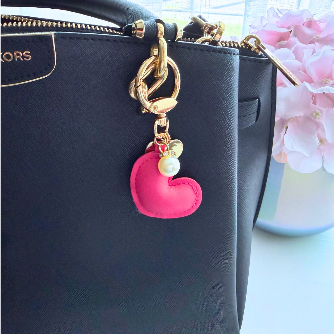 Pink heart purse charm attached to a black handbag showing how the charm looks during everyday use.