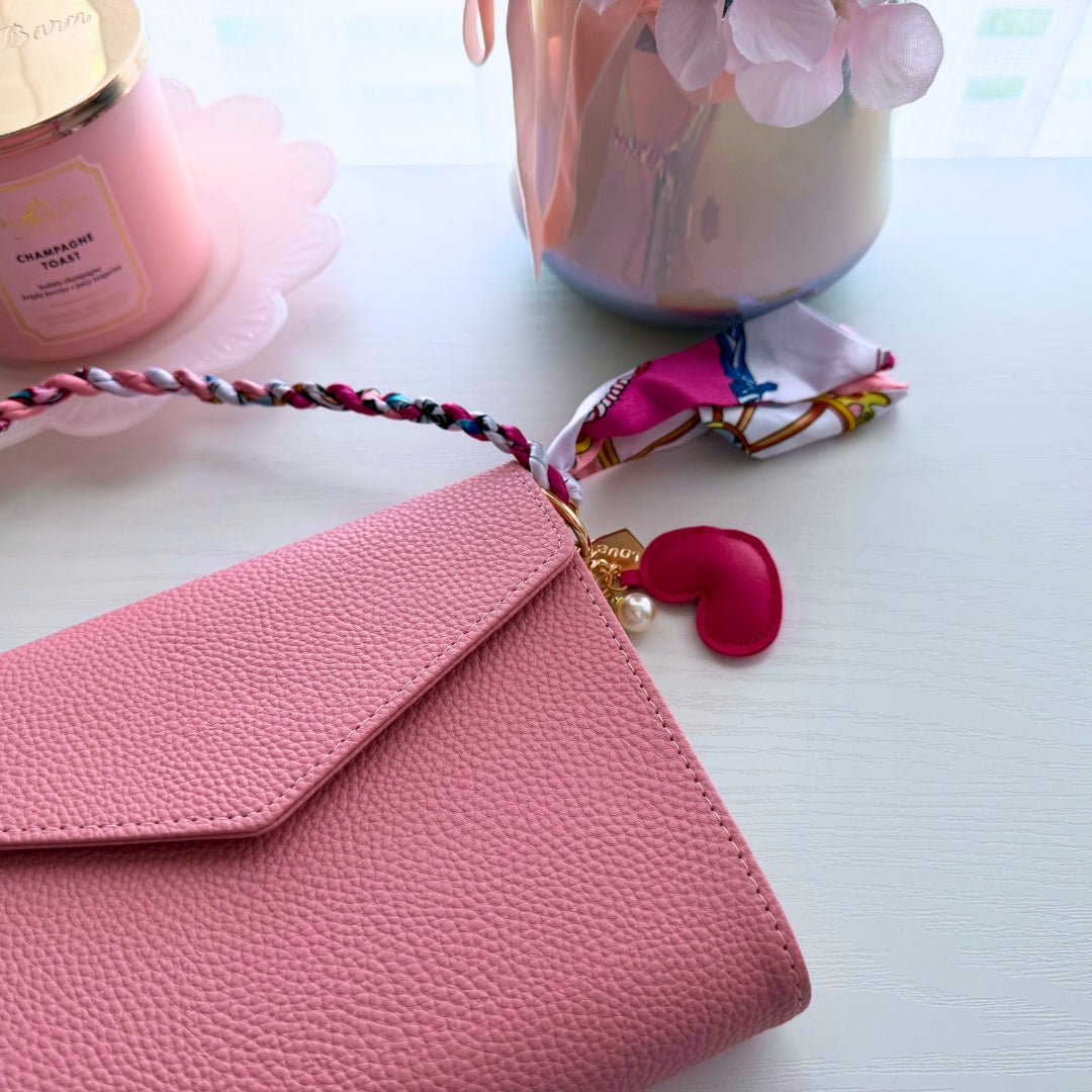 Pink heart purse charm displayed with a pink Bailey clutch showing the accessory paired with a feminine handbag.