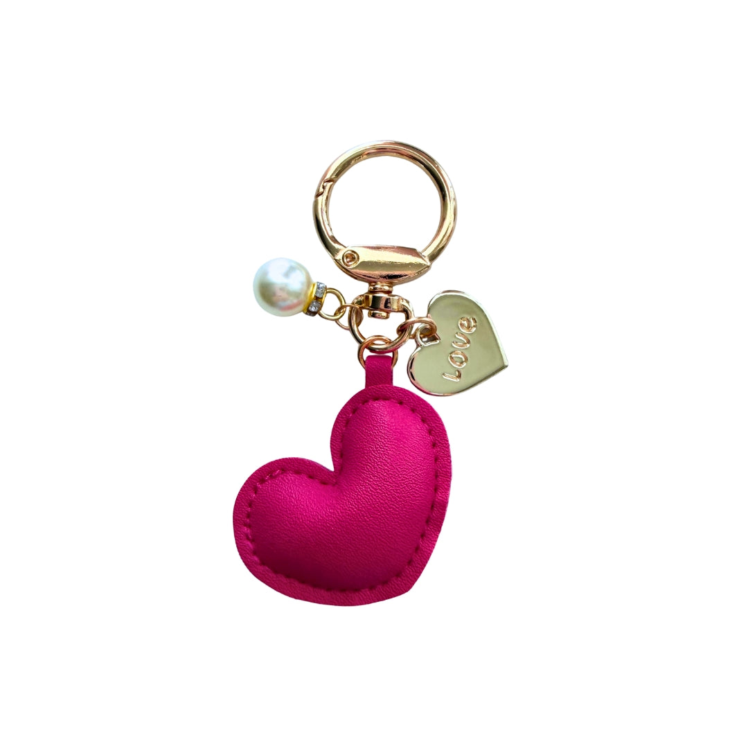 Handmade pink faux leather heart purse charm with pearl accent and gold Love heart charm on a white background.