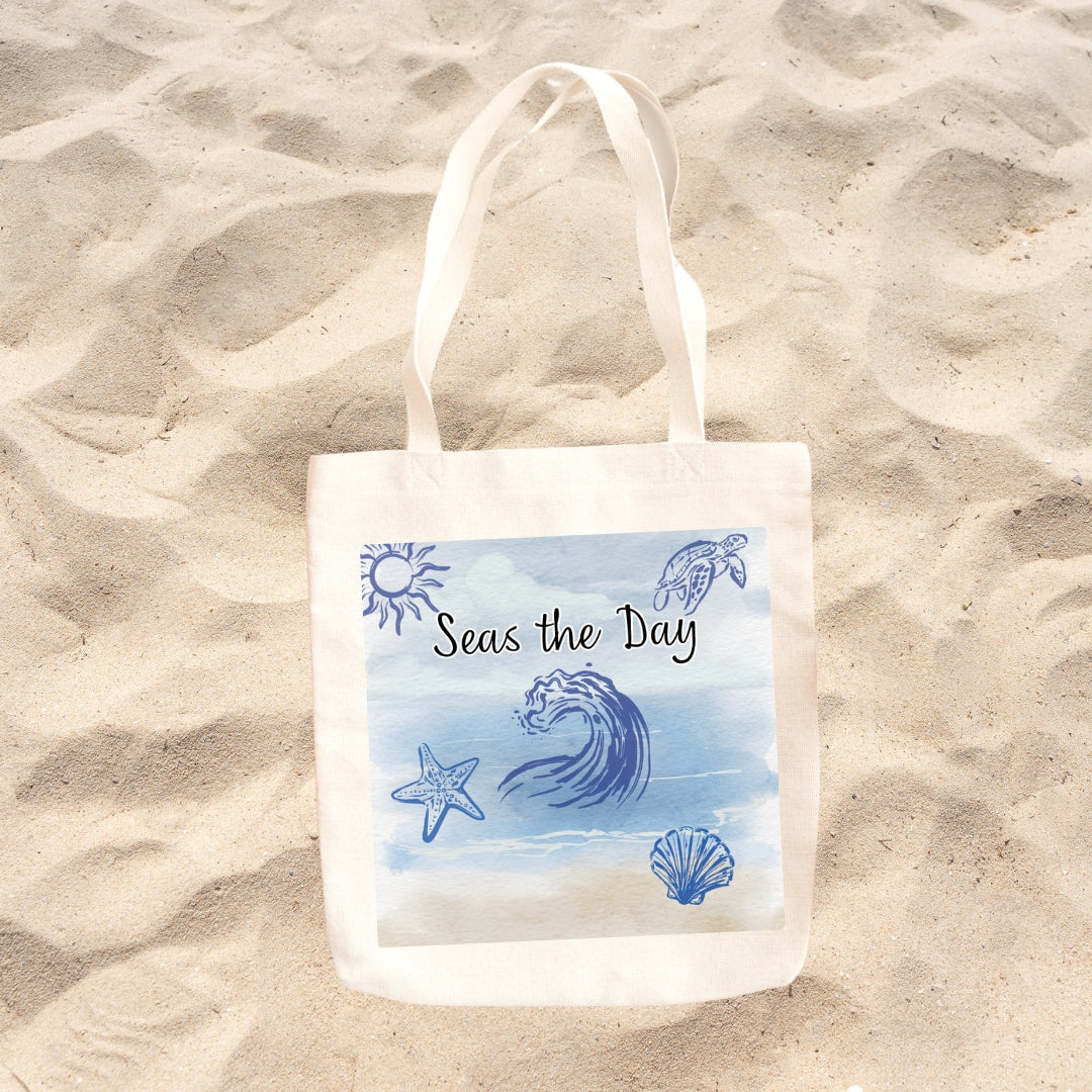 Canvas beach tote featuring the Seas the Day watercolor coastal design displayed on the sand at the beach.