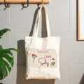 Tote hanging on wall hook with words "sweet but salty" on top of image of vintage paper.