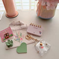 Tiny Tote Self-Care Bundle styled with mini tote, notepad, hair clip, charm accessories, and cozy pink aesthetic